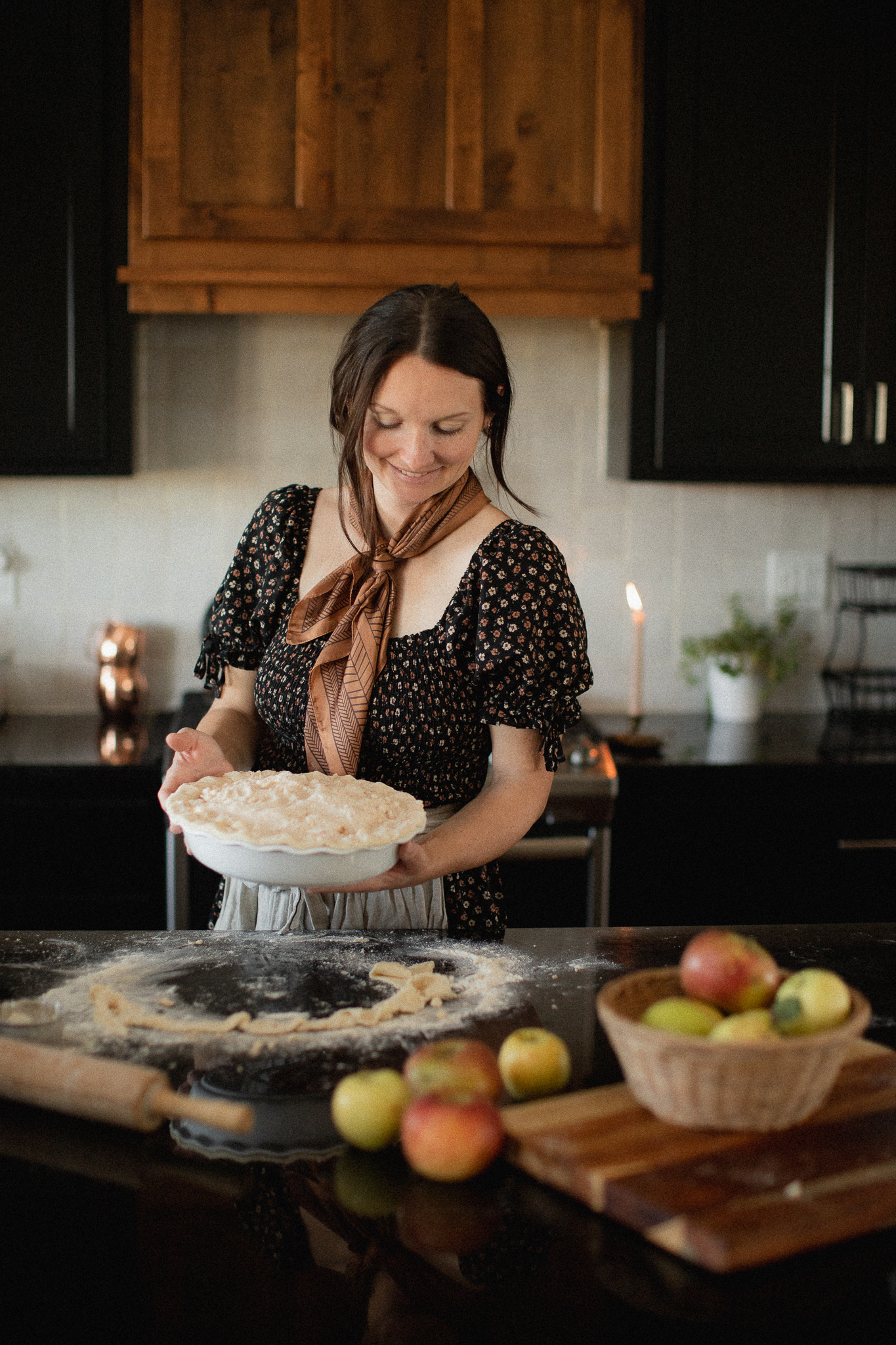 woman holding an apple pie in a kitchen